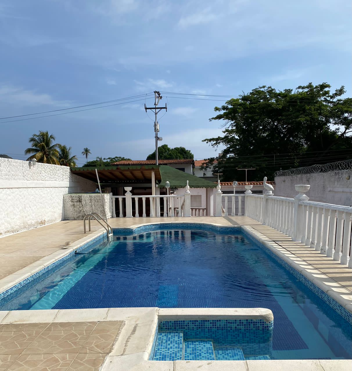Piscina rectangular con mosaicos azules y balaustrada blanca